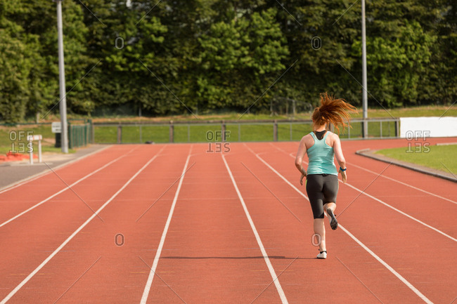 Rear view of female athletic running on sports track