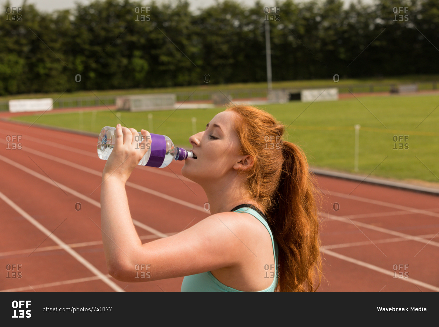 Young female athletic drinking water on running track