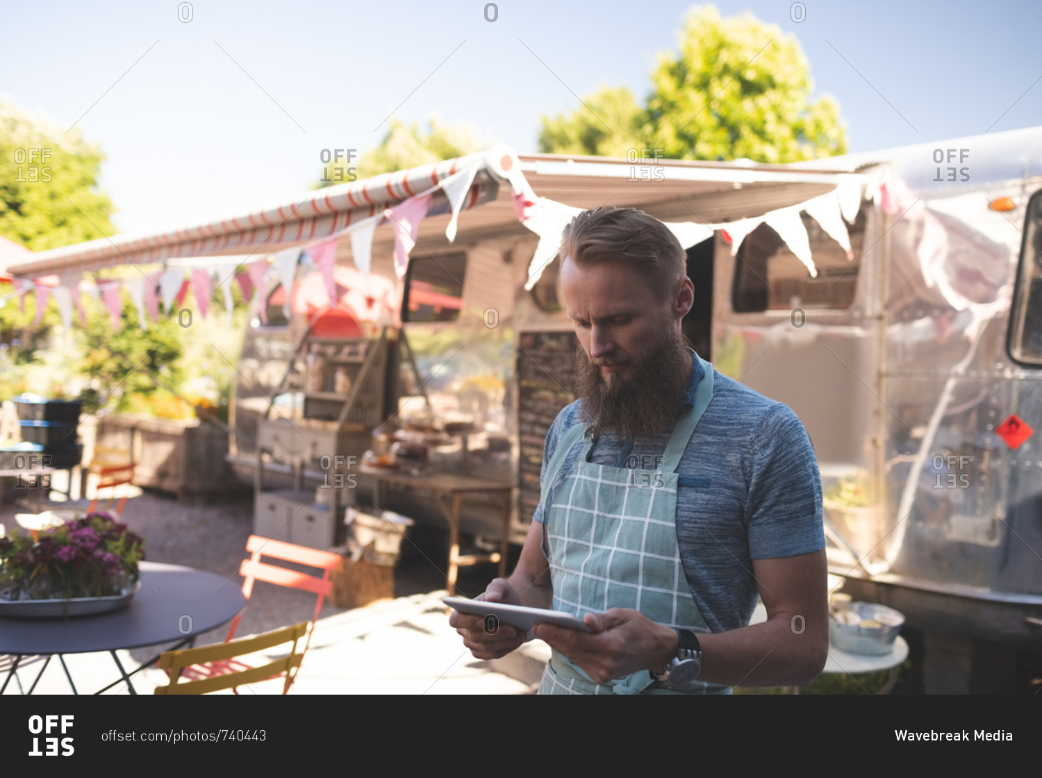 Attentive male waiter using digital tablet near food truck