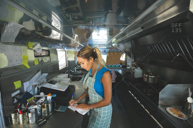 Woman waitress writing orders on notepad in food truck