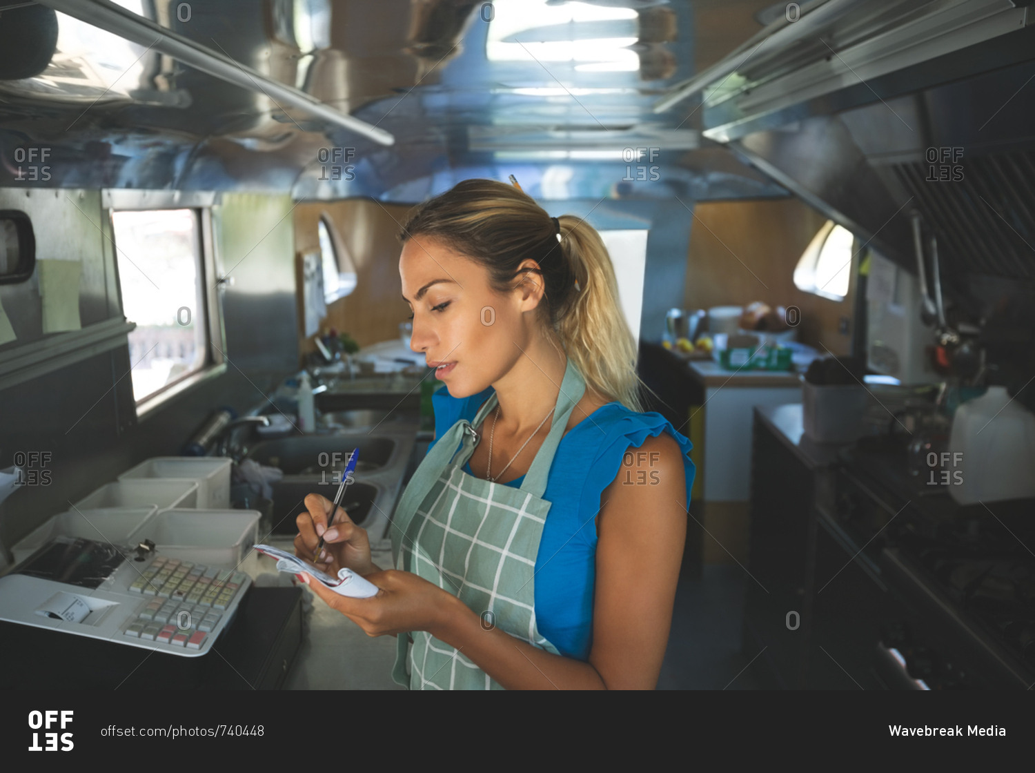 Woman waitress writing orders on notepad in food truck