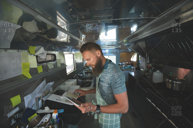 Waiter using digital tablet while operating billing machine in food truck