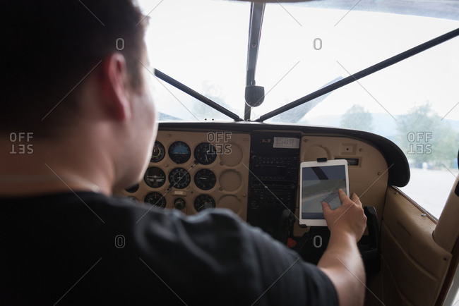 Rear view of pilot using digital tablet in cockpit