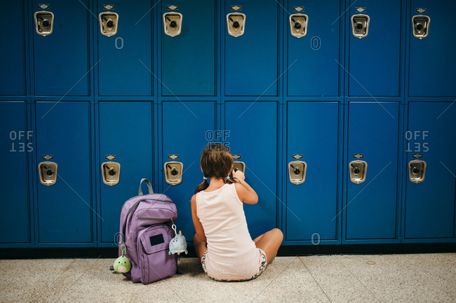 Girl sitting on the floor unlocking a locker