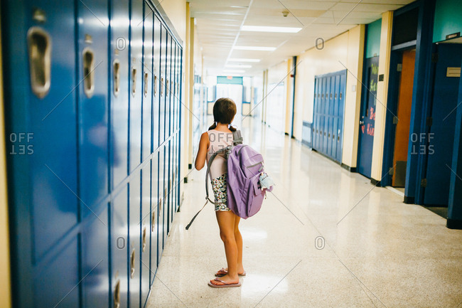Girl standing in school hallway by lockers