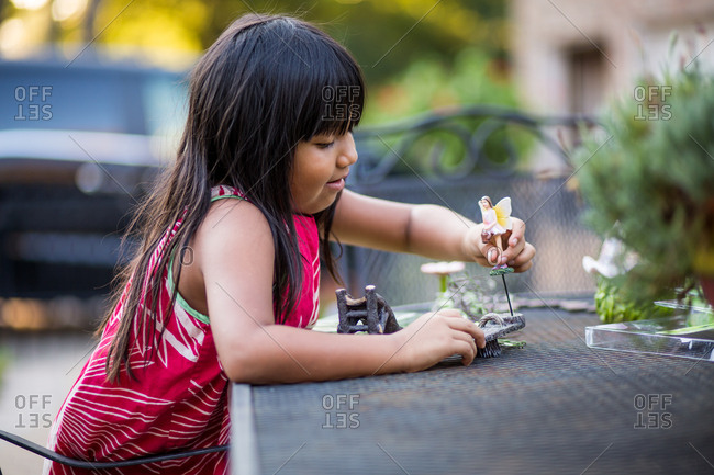 Girl arranging garden figurine and decor