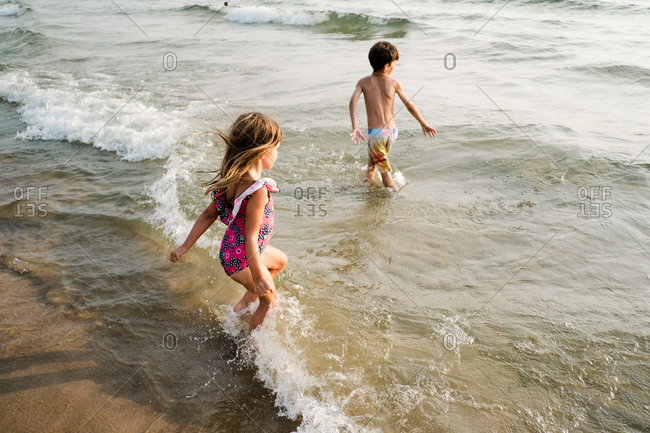 Children wading in the water together at the beach