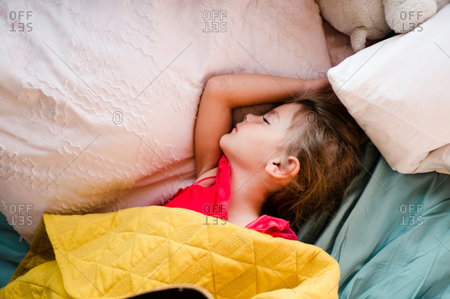 Girl sleeping in bed with pillows and blanket
