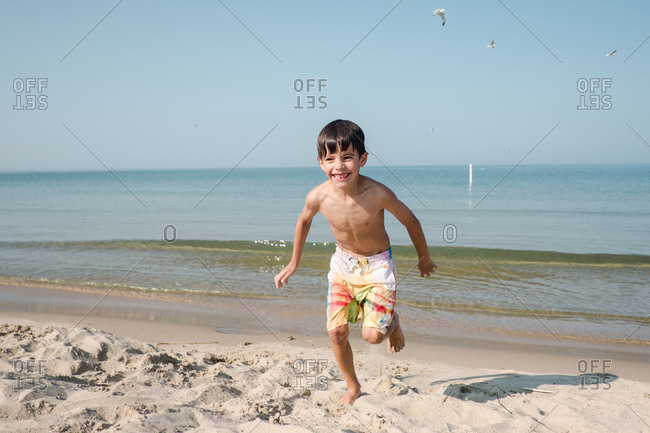 Smiling boy running from waves on the beach