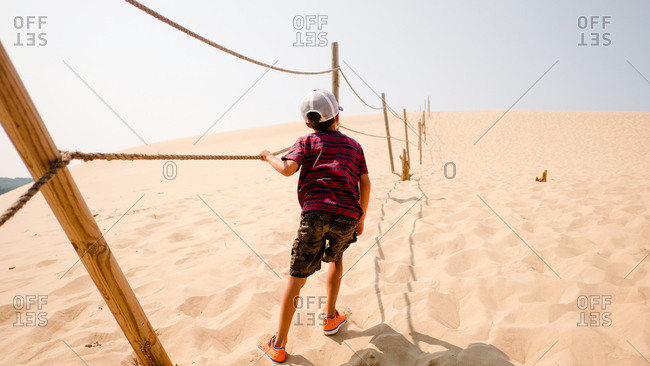 Child holding on rope to guide through sand dunes