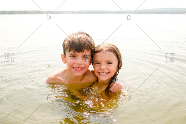 Portrait of brother and sister swimming together outdoors