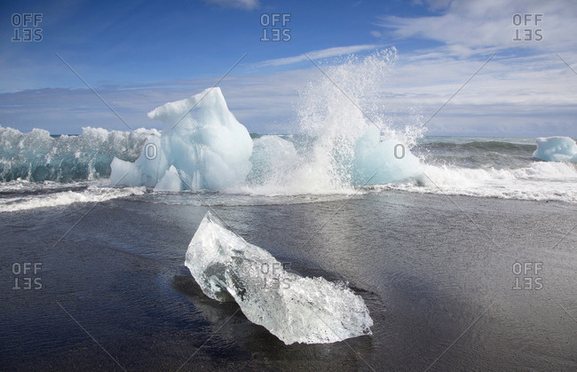 Iceberg breaking apart and crashing into the ocean at Jokulsarlon Lagoon in Iceland