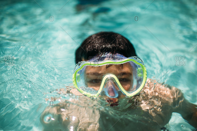 Boy swimming in a pool wearing goggles