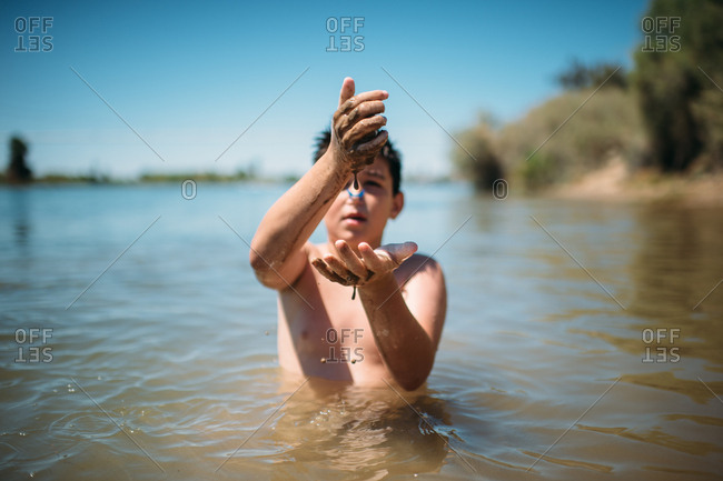 Boy swimming in a lake and playing with mud