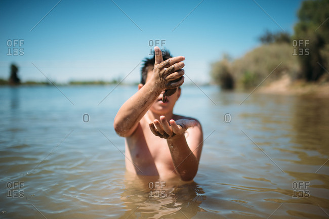 Boy playing with mud in a lake