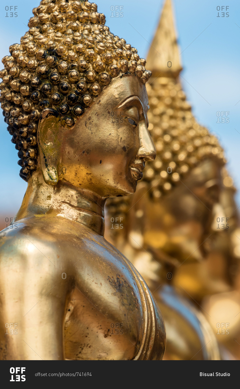 Bright shiny statues of golden Buddha placed in row, Thailand stock