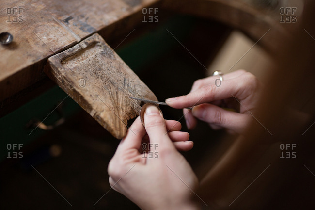 Crop close up hands of woman carving and brushing little detail with brush at desk
