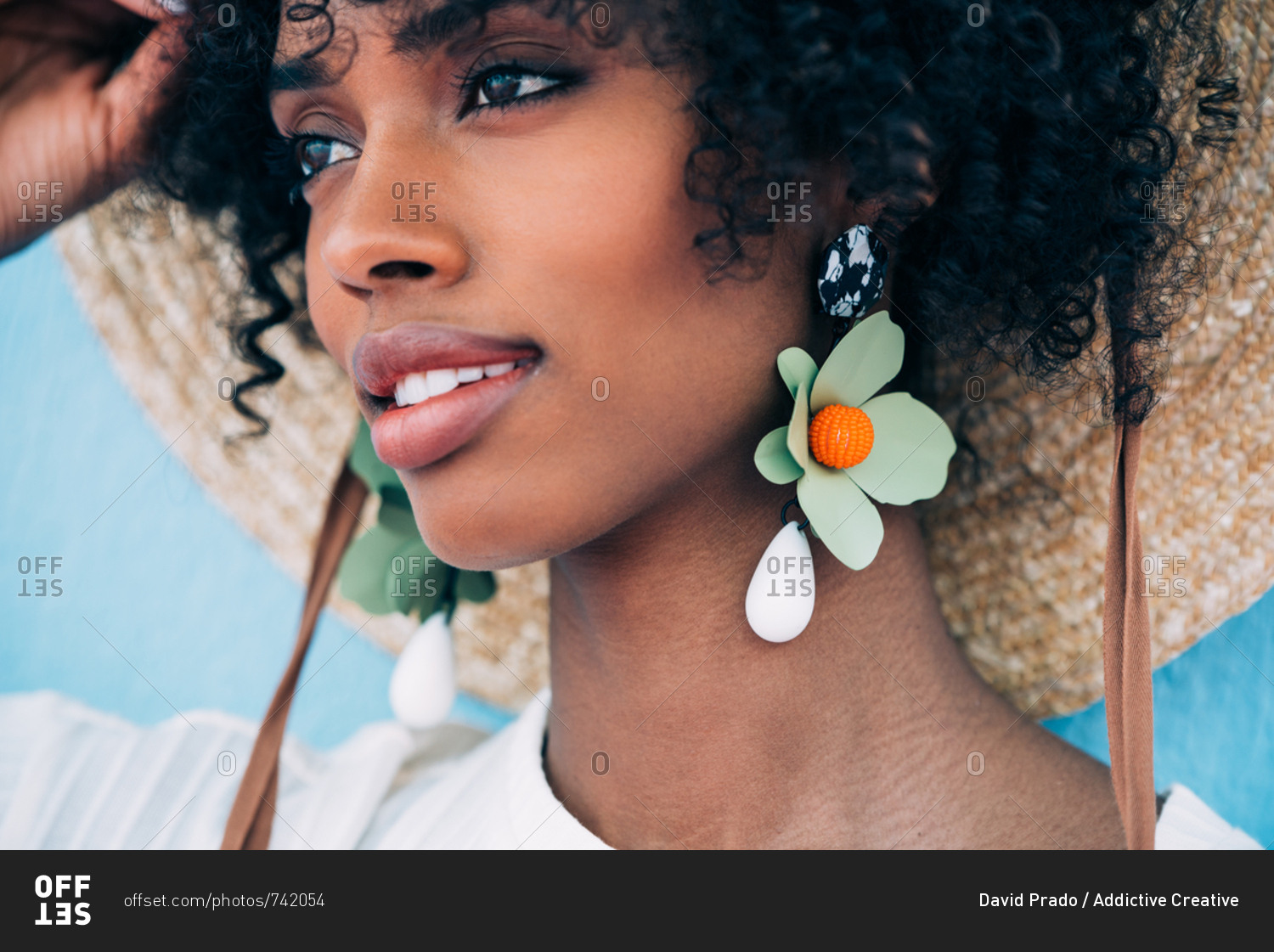 Beautiful black woman wearing big earrings and a straw hat