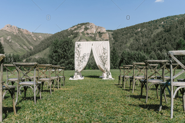 Wedding ceremony with a square arch and wooden chairs. rustic wedding in nature. mountain and forest view