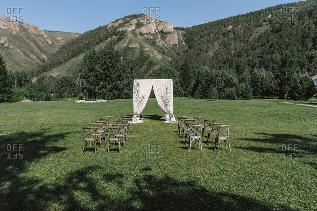 Wedding ceremony with a square arch and wooden chairs. rustic wedding in nature. mountain and forest view