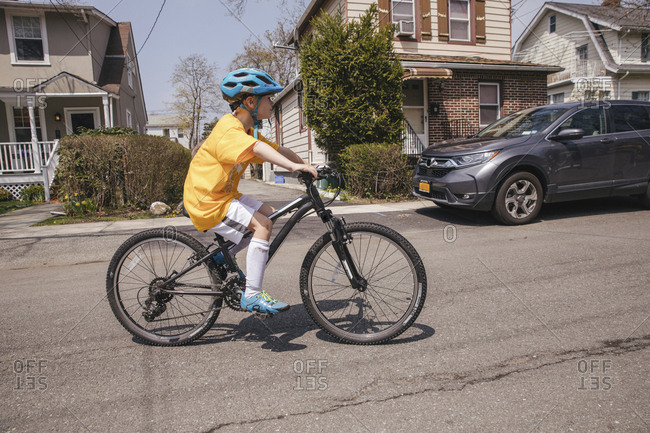 Side view of boy riding bicycle on street during sunny day