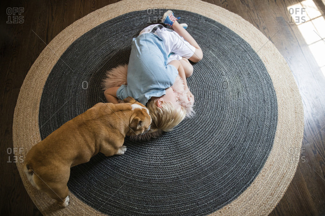 High angle view of pug standing by boy sleeping on carpet at home