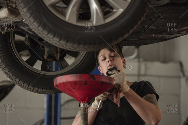 Female mechanic holding work tool while repairing car in auto repair shop