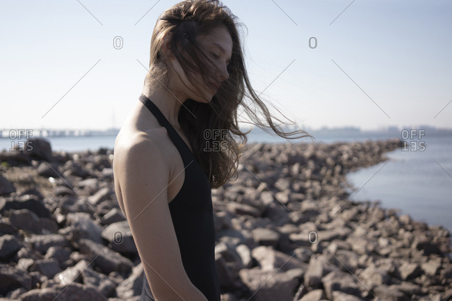 Side View Of Young Woman With Tousled Hair Standing At Beach