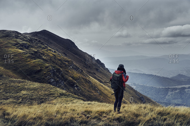 Rear view of female hiker with backpack standing on Balkan Mountains against cloudy sky