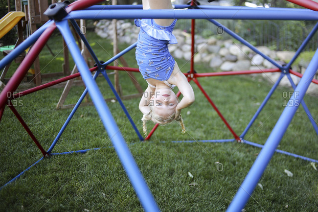 Portrait of cute girl hanging upside down on jungle gym at playground