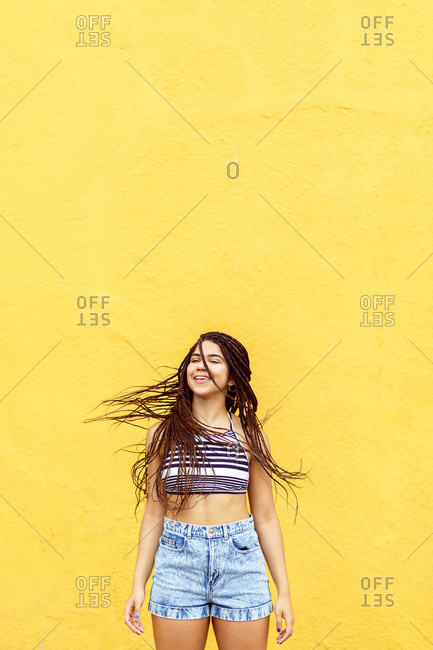 Girl swinging hair in front of yellow wall