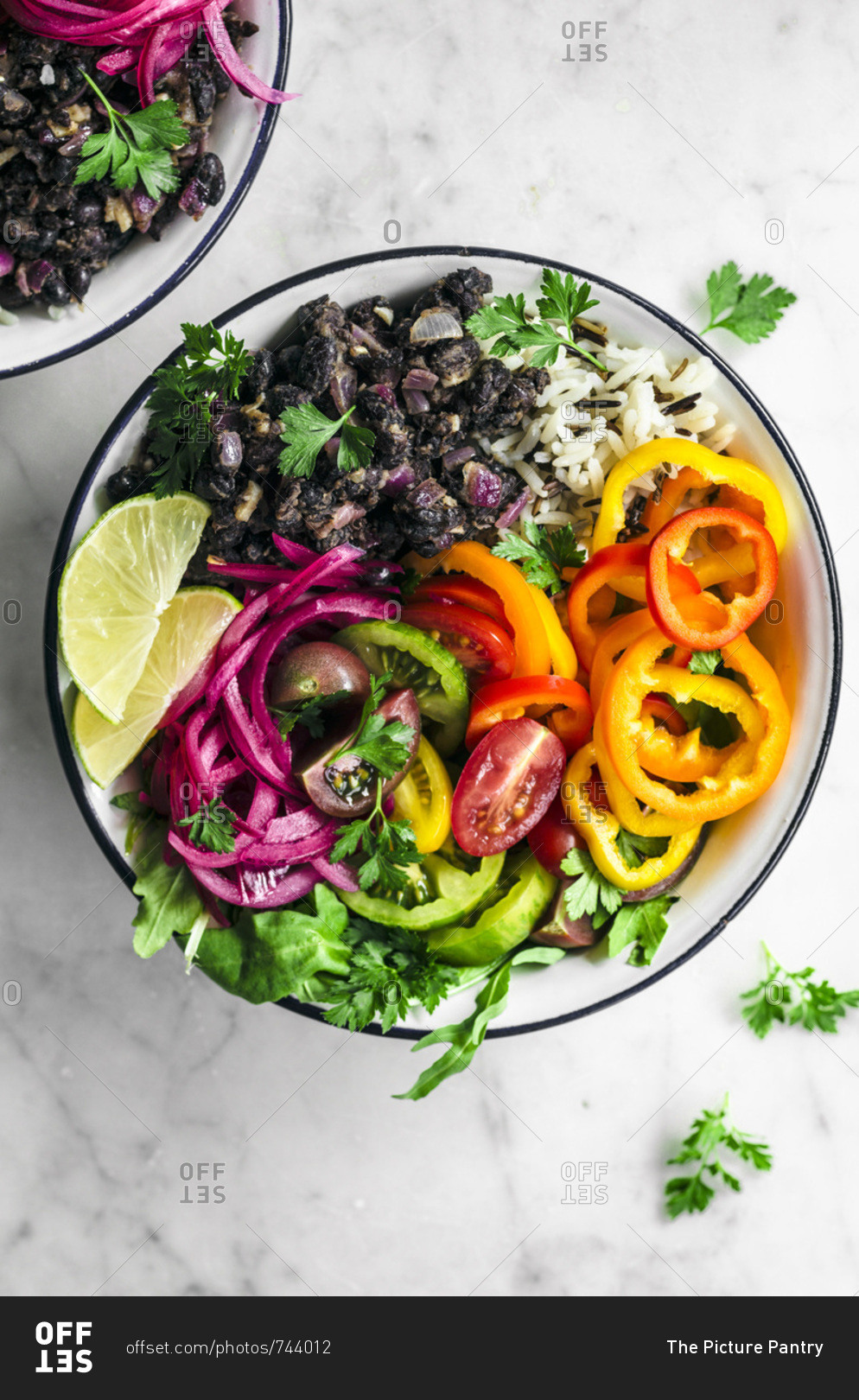 Vegan burrito bowls with spicy black beans, rice, summer vegetables, and pickled onions