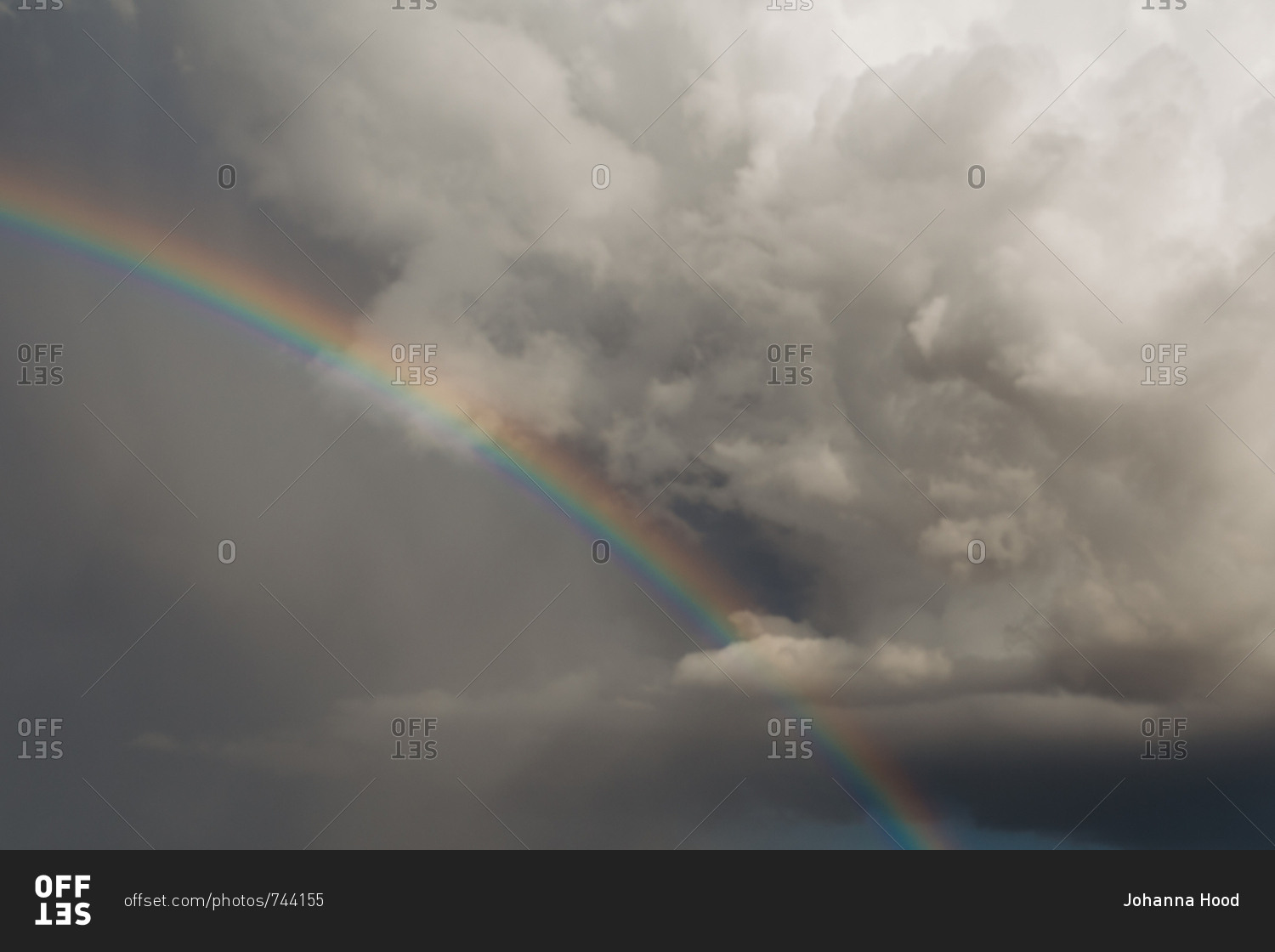 Bright rainbow against dark storm cloud in the sky