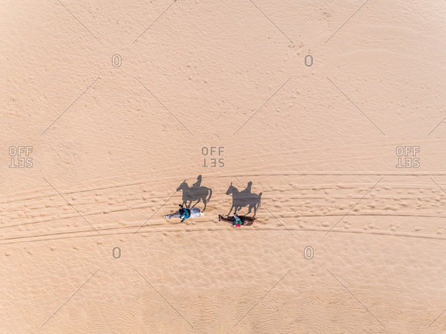 Aerial view of two people riding horses in desert, Abu Dhabi, UAE.