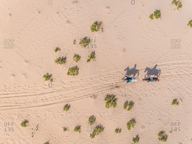 Aerial view of two people riding horses in desert, Abu dhabi, UAE.