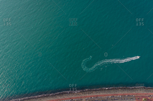 Aerial abstract view of speed boat and water trail by long road in Dubai, UAE.