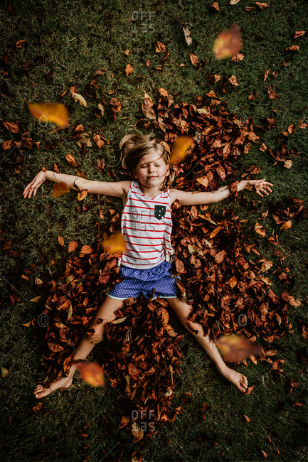 Little girl playing in a pile of leaves