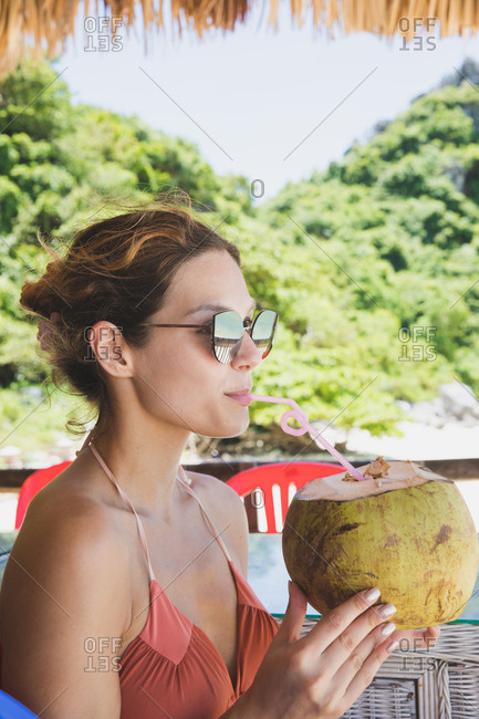 Girl drinking from a coconut on the beach