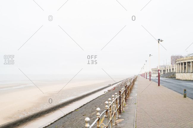 Promenade along sandy beach on a foggy day