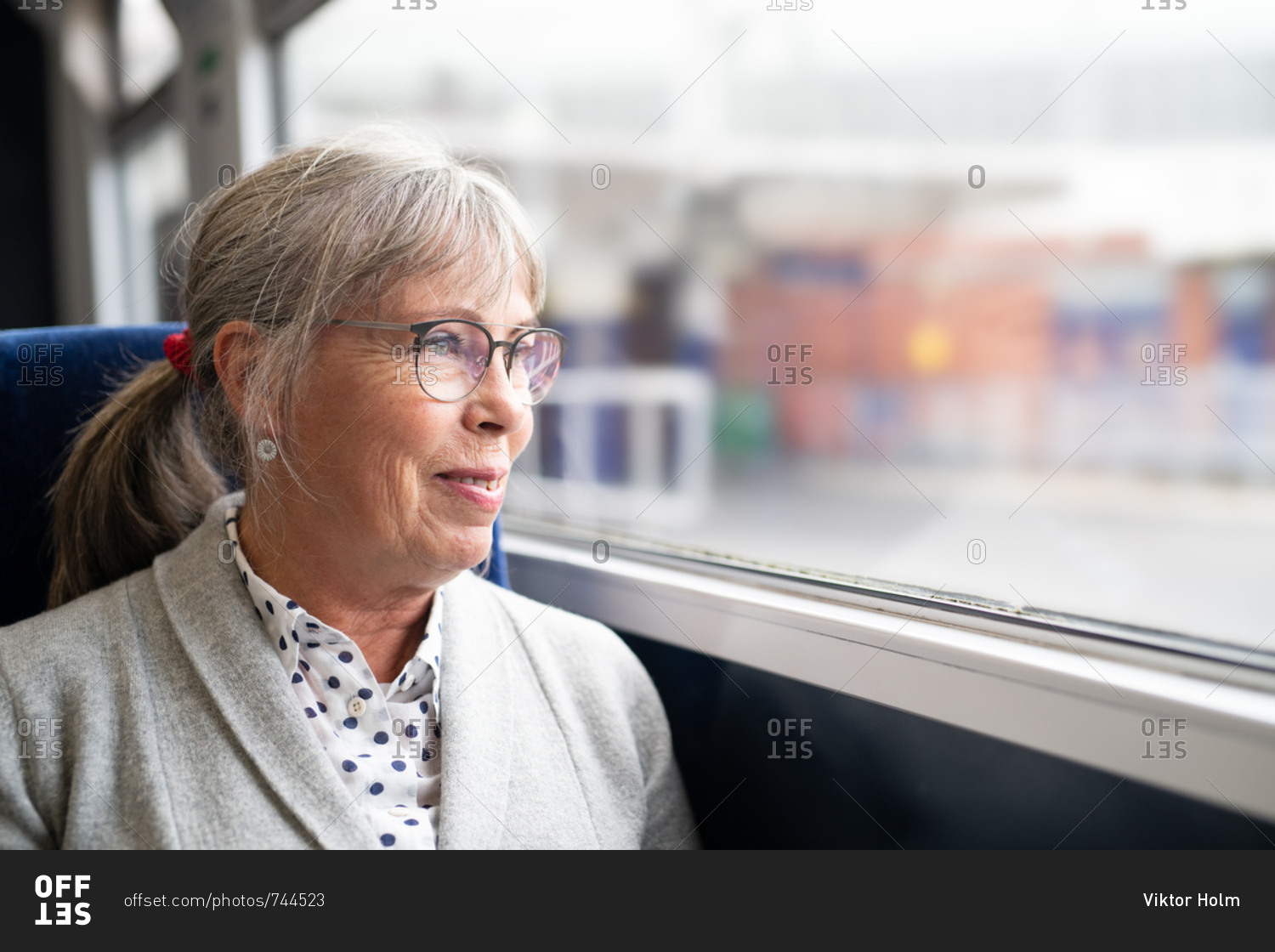 Smiling senior woman looking out window of train