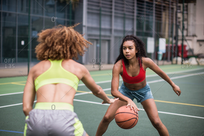Young adult females playing basketball