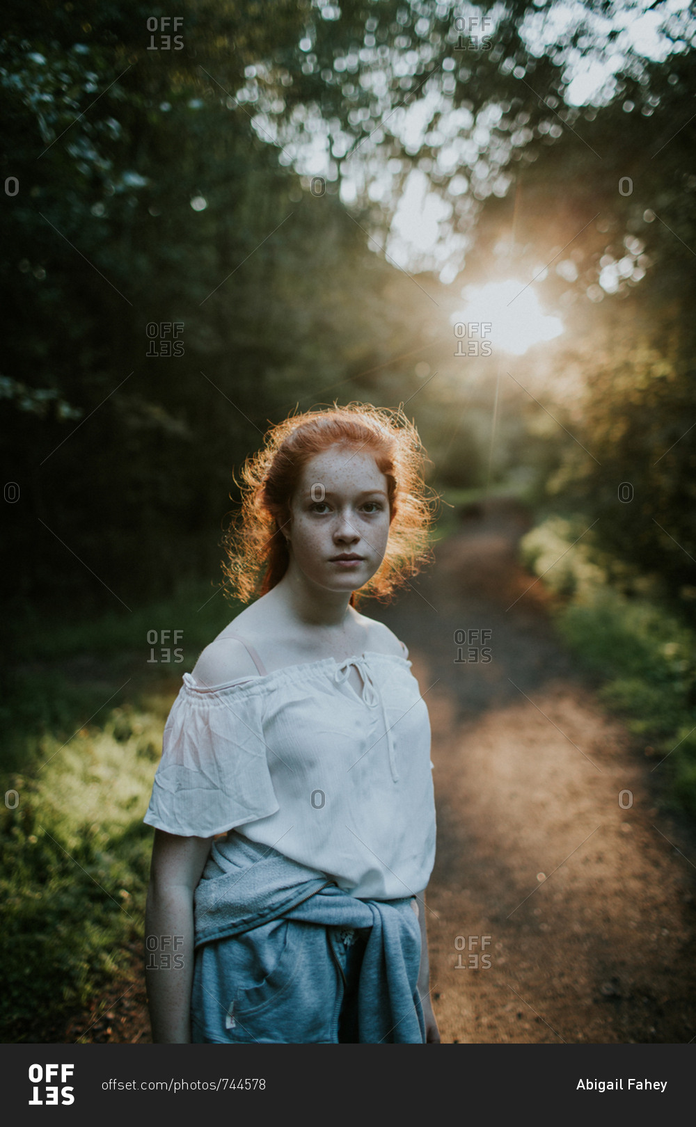 Portrait of a redheaded girl wearing off-shoulder blouse at sunset