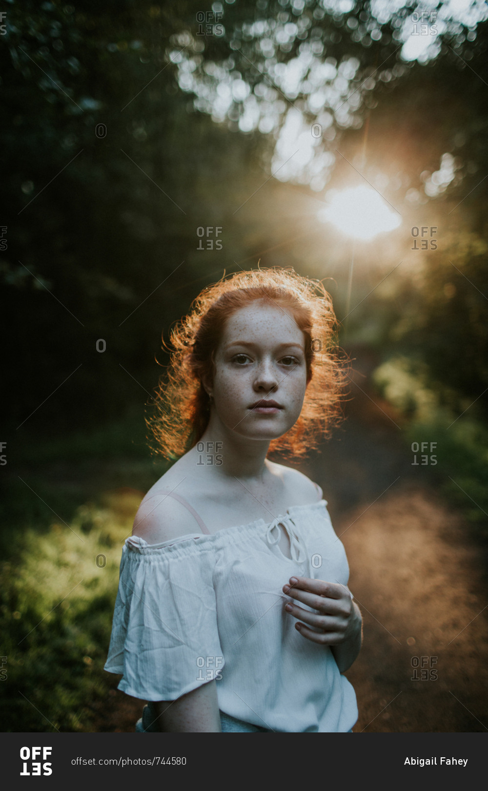 Portrait of a ginger girl wearing off-shoulder blouse at sunset