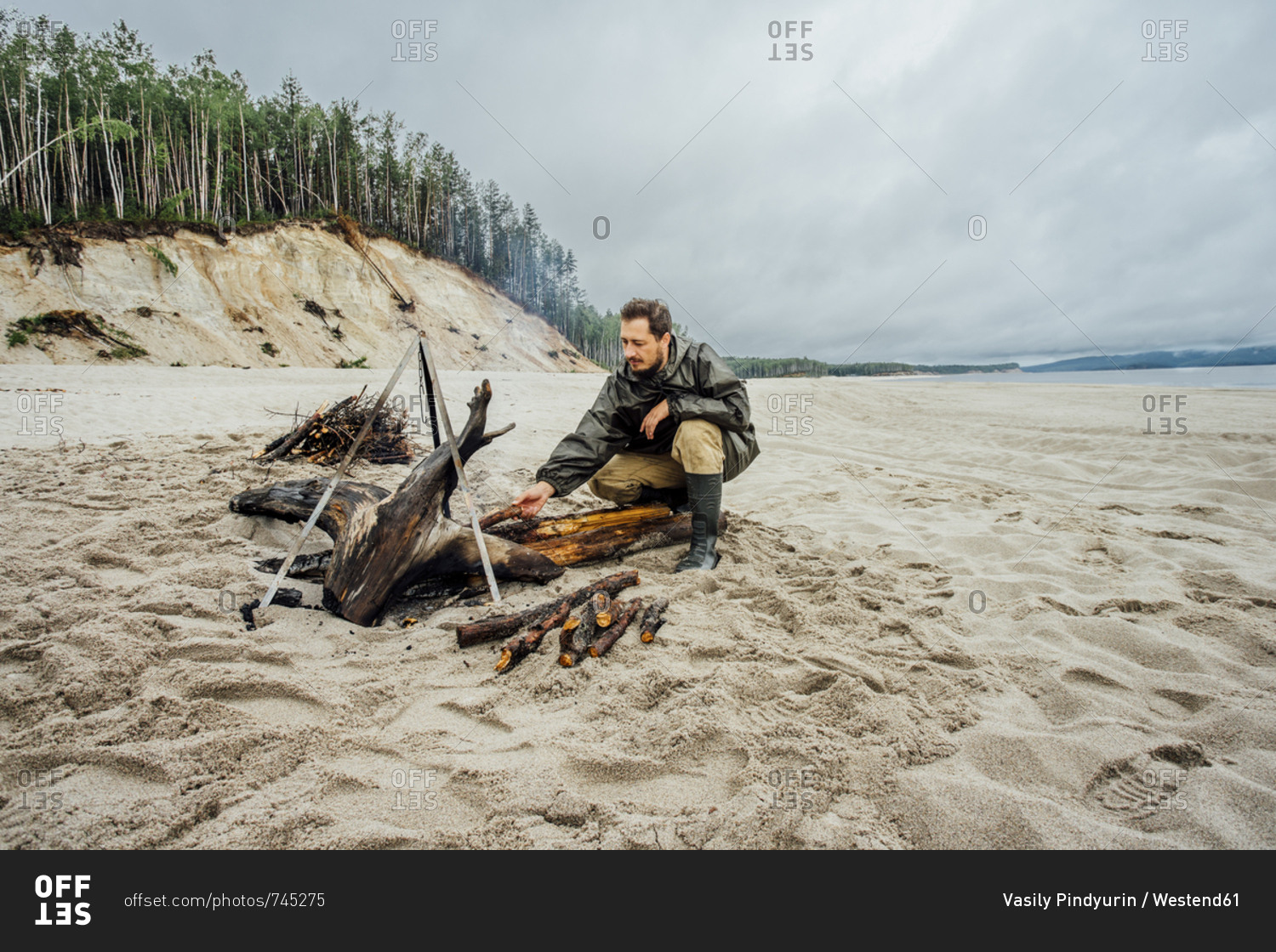 Man collecting firewood on the beach- preparing campfire