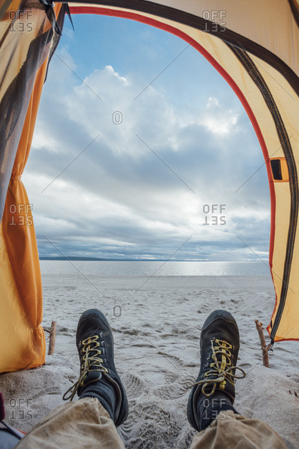 Feet of man- lying in tent on beach