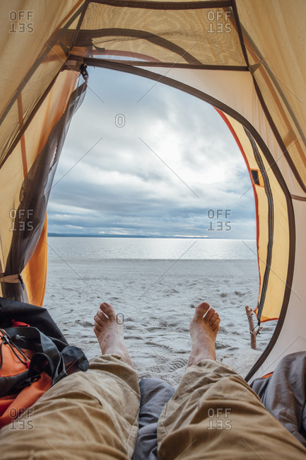 Feet of man- lying in tent on beach