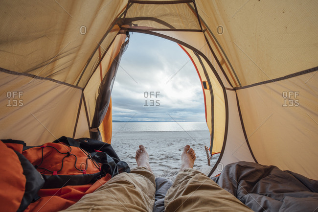 Feet of man- lying in tent on beach