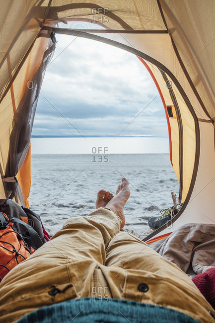 Feet of man- lying in tent on beach