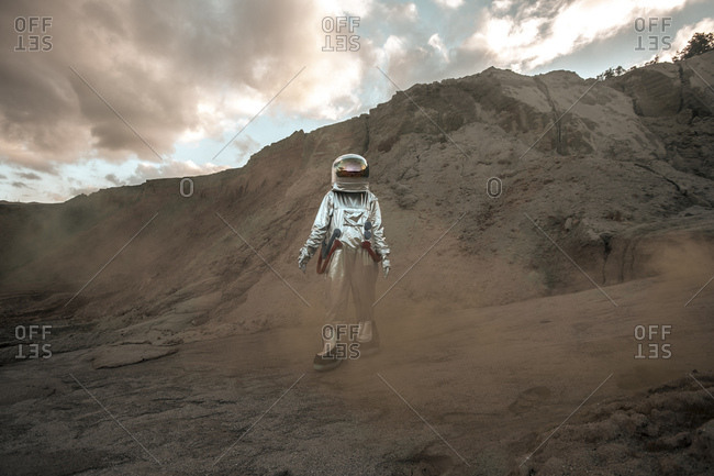 Spaceman exploring nameless planet- walking in a dust cloud