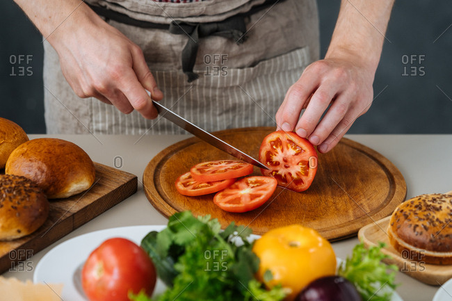 Chef slicing tomatoes for burgers